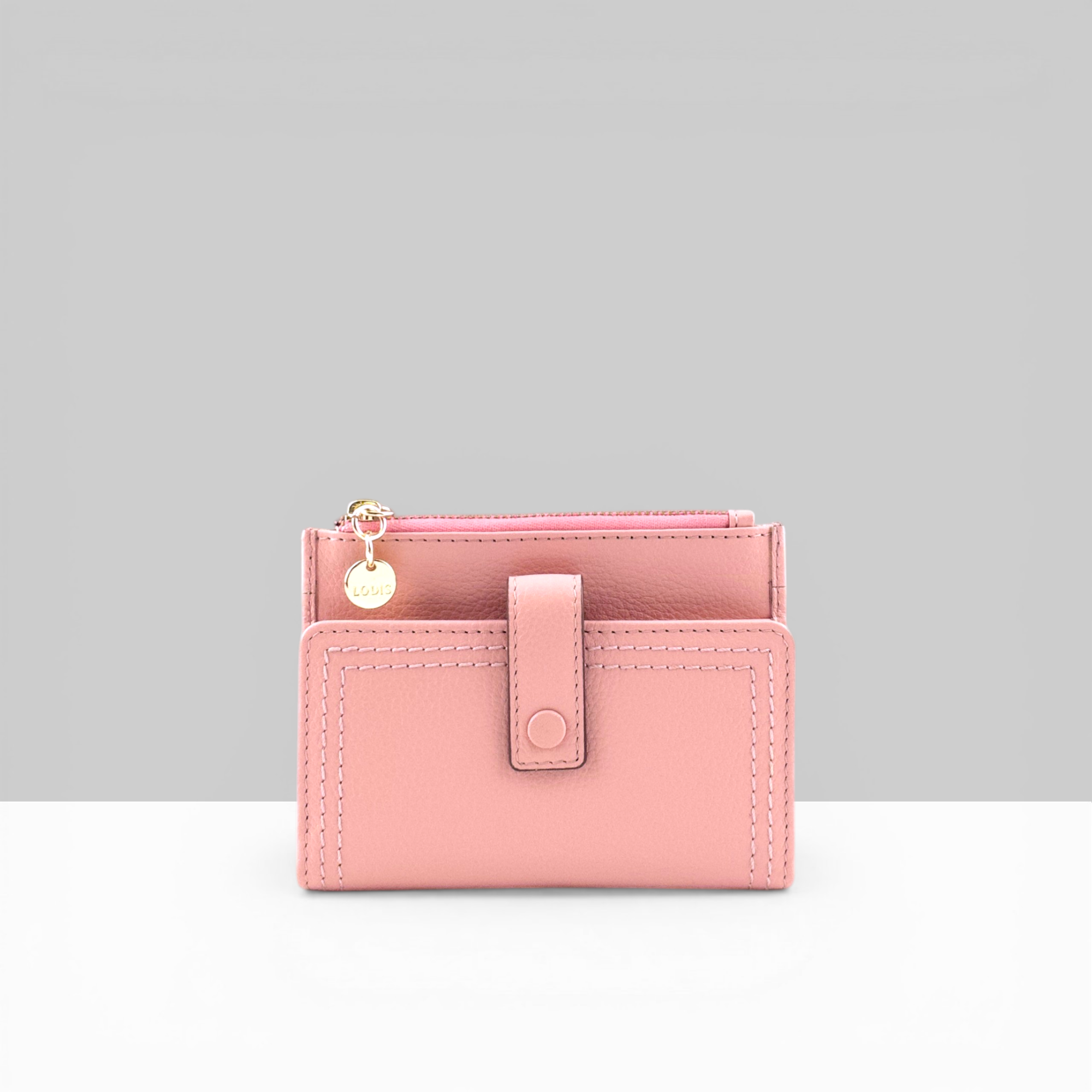 Lodis Kiara Flip Face Wallet in fondant pink pebbled leather with tab strap, snap closure, and gold Lodis charm – front view