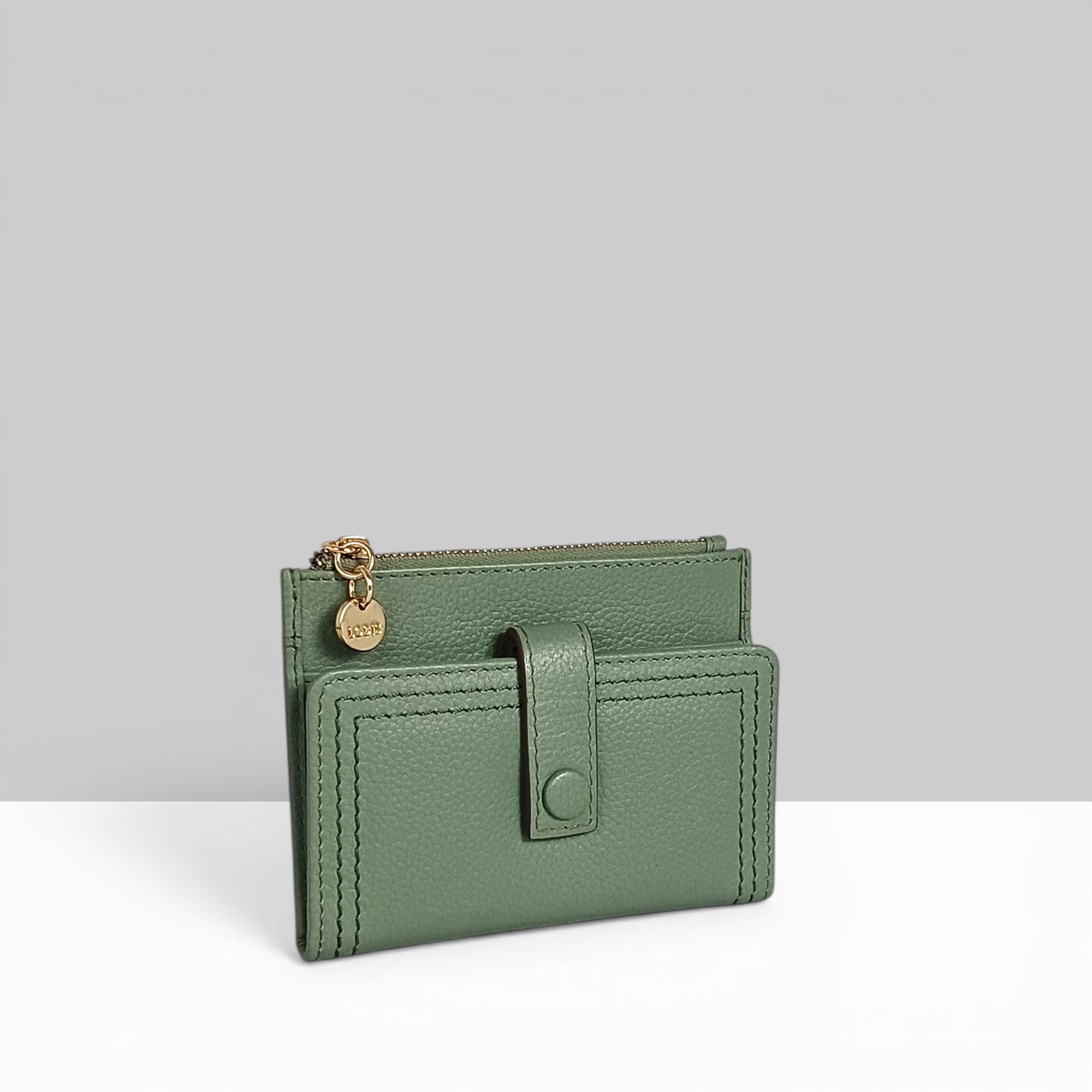Lodis Kiara Flip Face Wallet in sage green pebbled leather with tab strap, snap closure, and gold zip top – side angle view