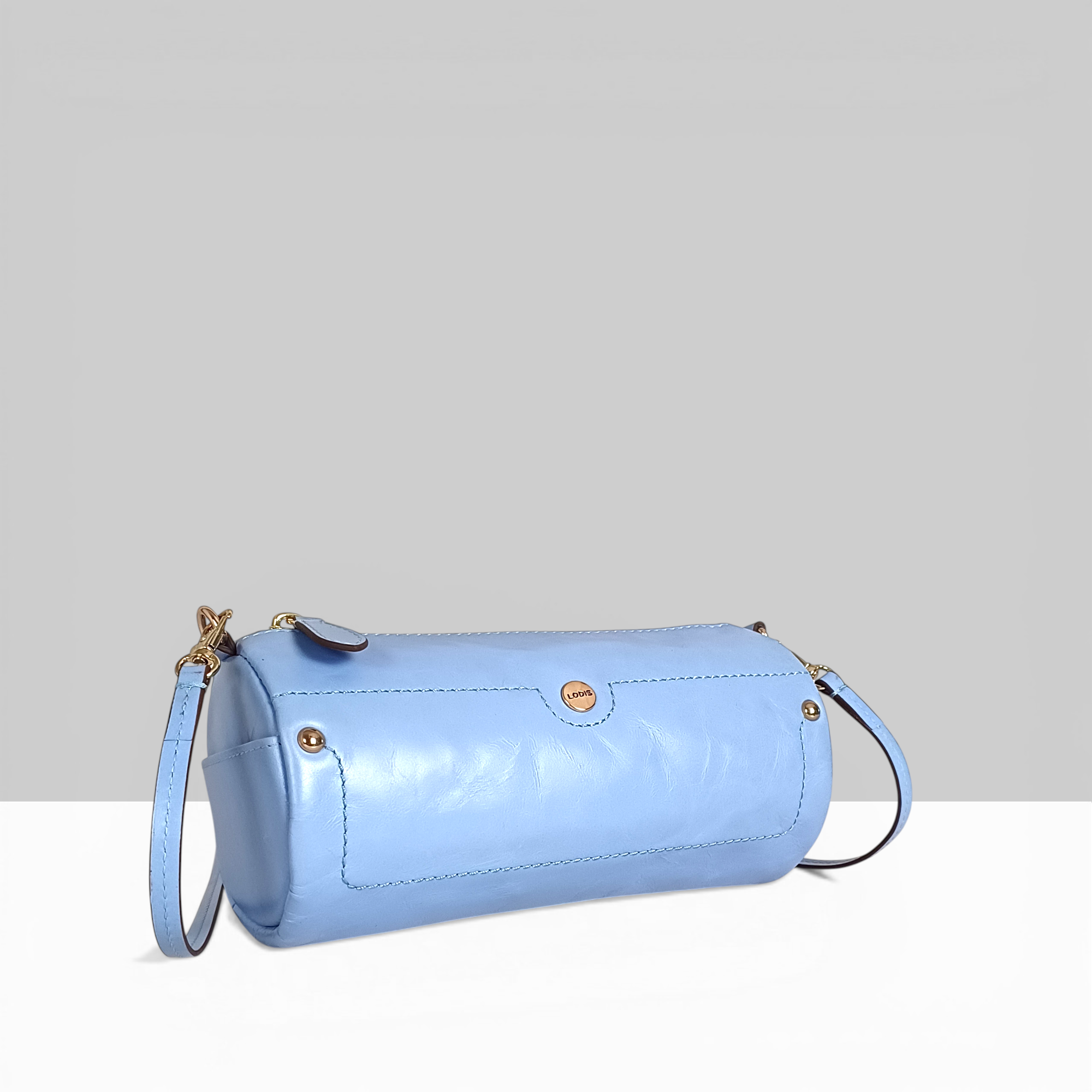 Lodis Overglow Barrel Sling in Light Blue Glossy Leather – Angled View with Crossbody Strap