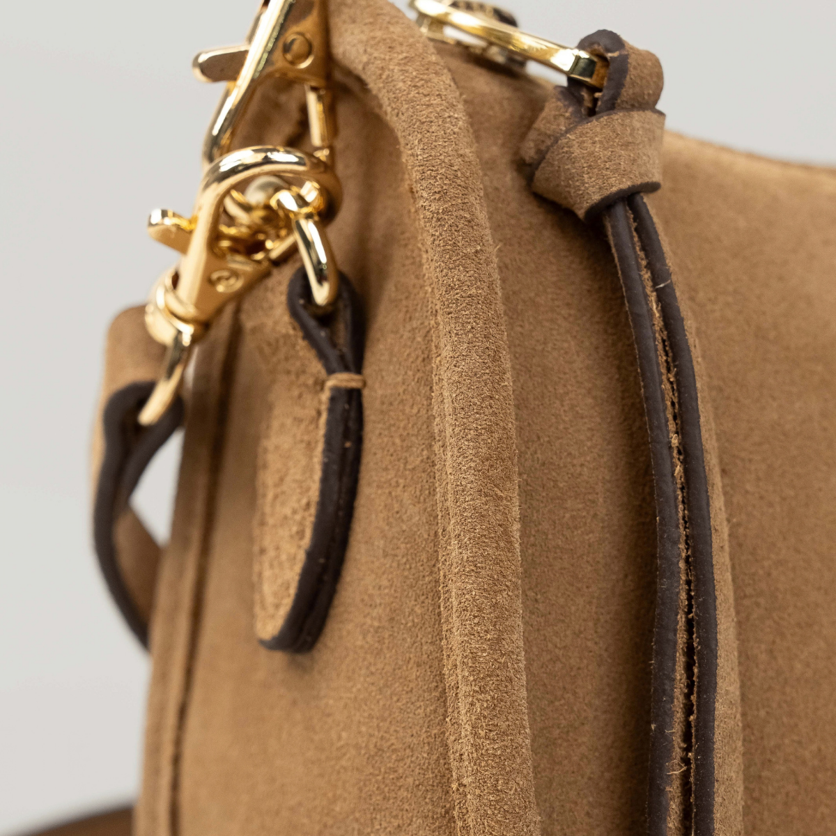 Lodis Axis Crossbody in Saddle - Side Detail of Gold-Tone Swivel Clasps and Texas Leather Strap Tab on Camel Suede | Lodis 1965
