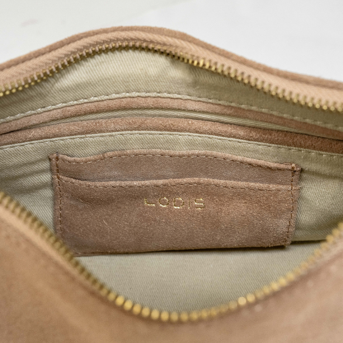 Lodis Axis Crossbody in Saddle - Interior View Showing Gold-Tone Zip Opening, Suede Slip Pocket with Lodis Logo and Light Fabric Lining | Lodis 1965
