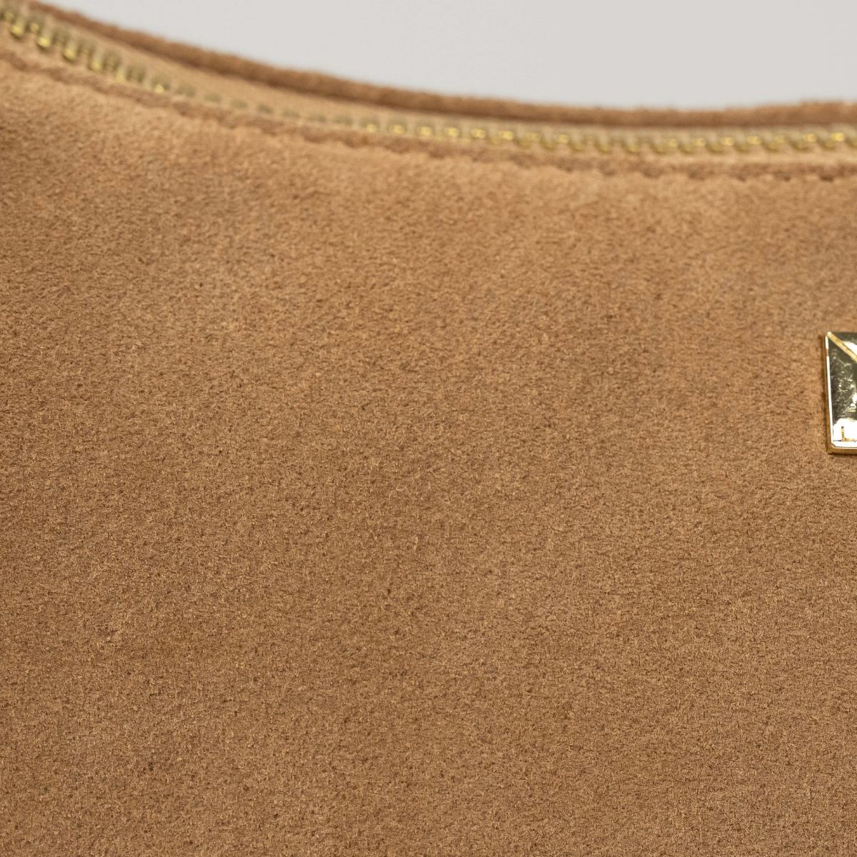 Lodis Axis Crossbody in Saddle - Close-Up of Camel Suede Texture with Gold-Tone Logo Plate and Zip Edge | Lodis 1965