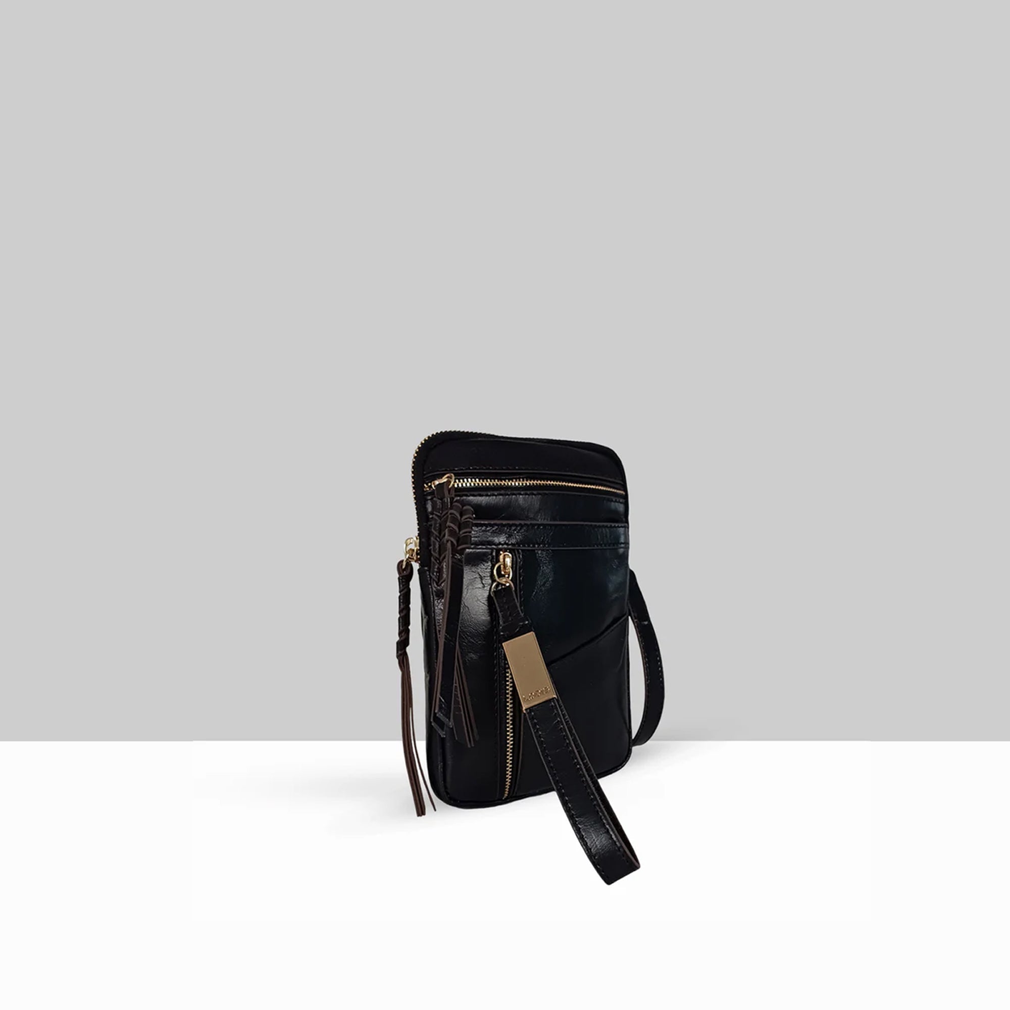 Lodis Catalina 2.0 Phone Crossbody in Black – Angled View Showing Zip Top, Front Zip Pocket, Gold-Tone Logo Plate, Tassel, and Wrist Strap Detail | Lodis 1965