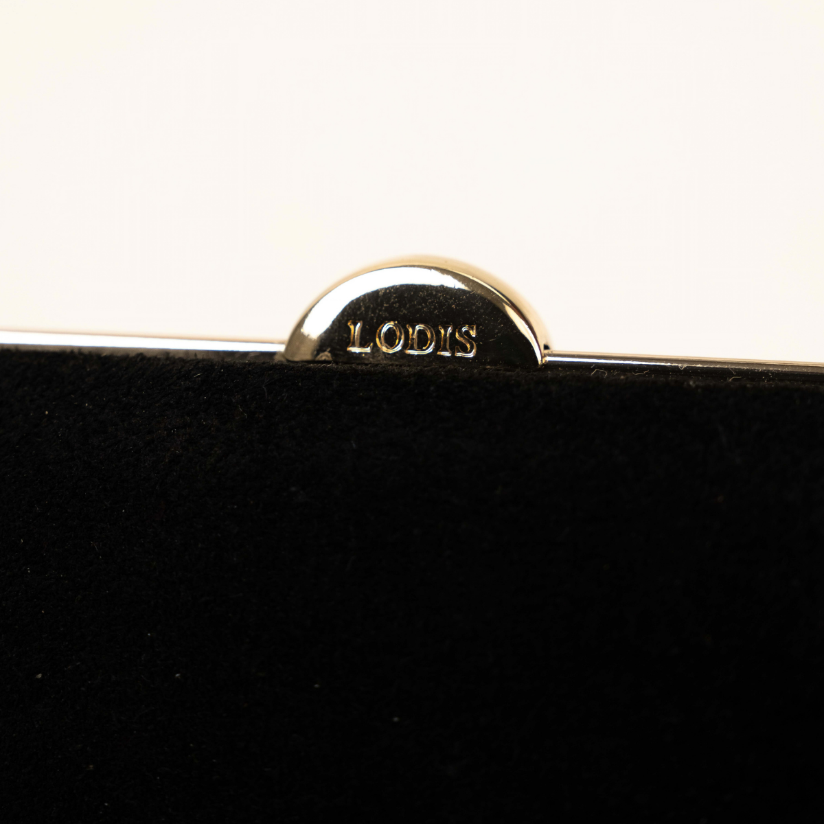 Lodis Celara Frame Clutch in Black - Close-Up of Polished Gold-Tone Half-Moon Clasp Engraved with Lodis Logo on Black Texas Suede | Lodis 1965