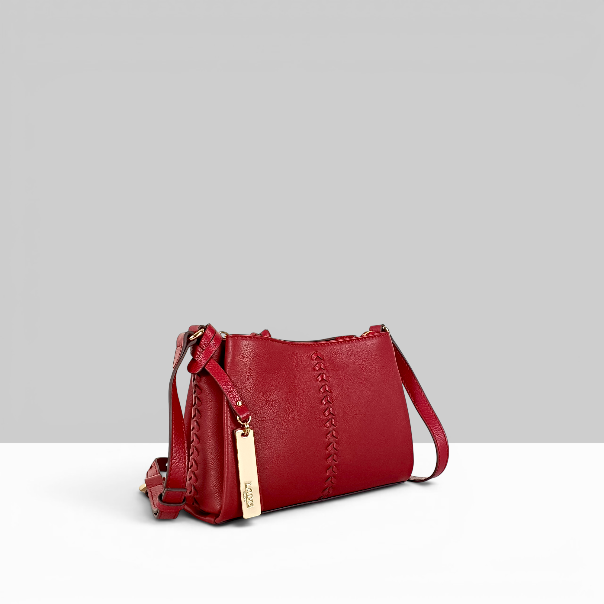 Lodis Nicks Crossbody in Rhythmic Red - Side Profile View Showing Whipstitch Detail, Adjustable Strap and Gold-Tone Logo Tag | Lodis 1965