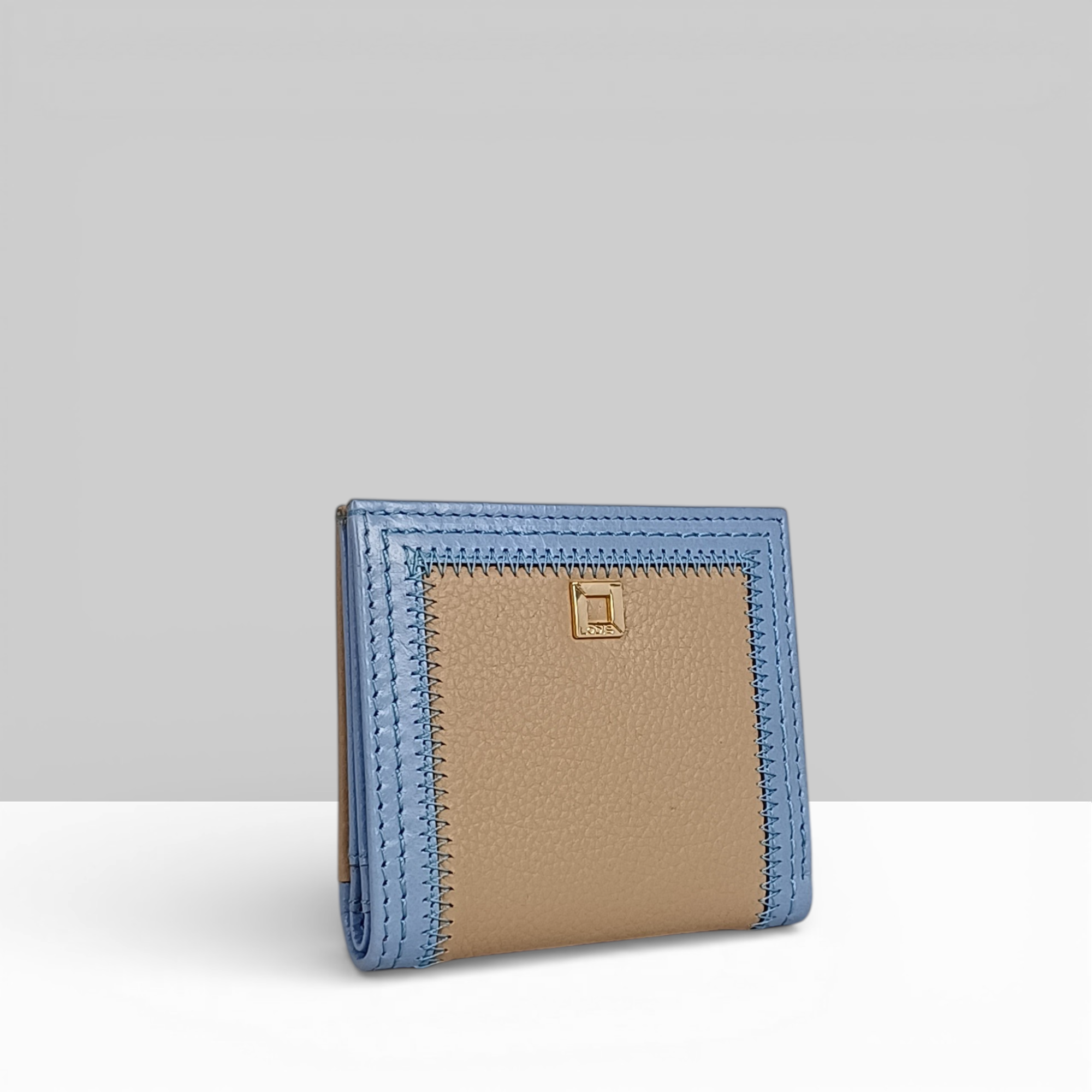 Cafe Slim Wallet in Aura Blue and Sand Two-Tone Leather – Angled Side View Showing Contrast Stitching Border and Gold Square Snap Detail | Lodis 1965