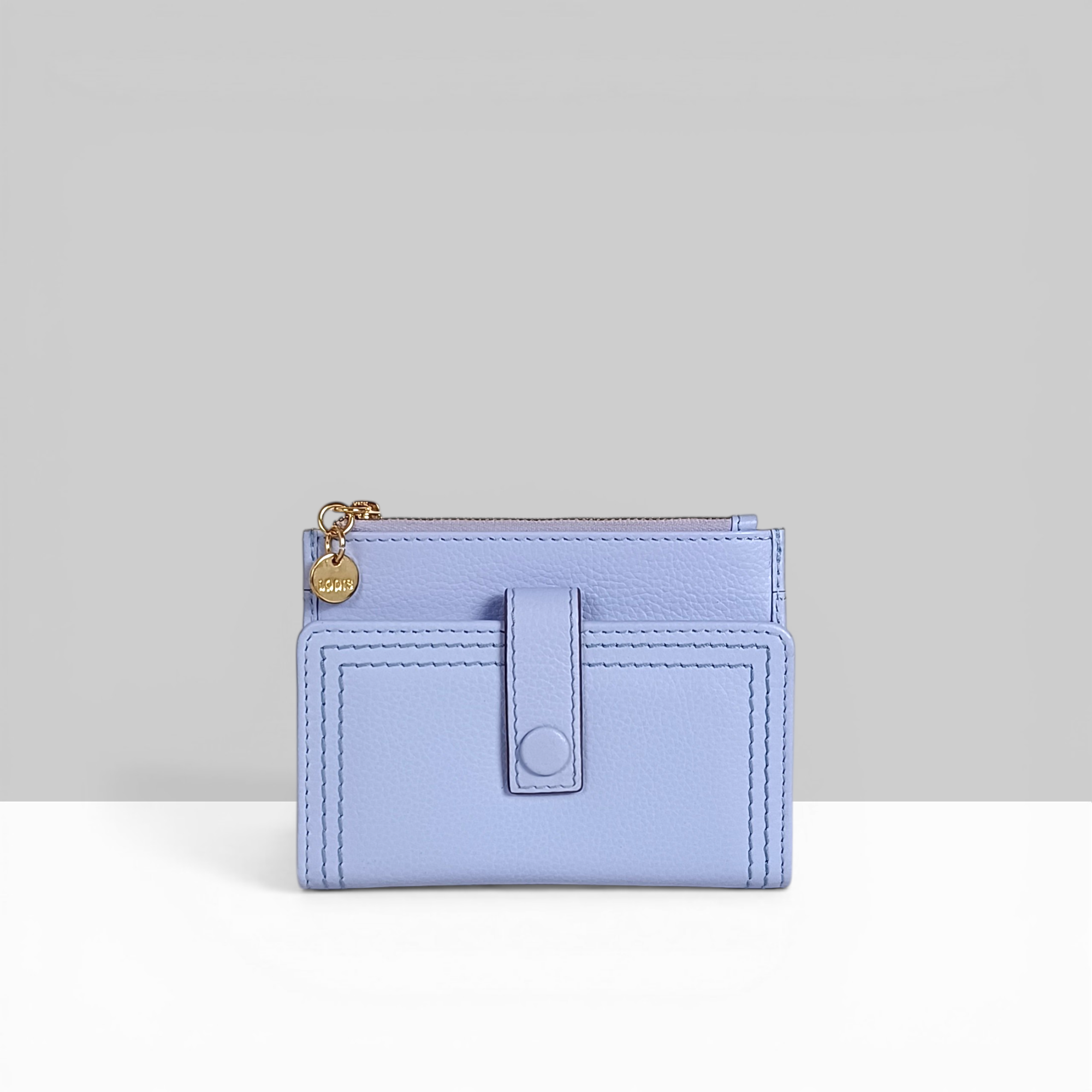 Lodis Kiara Flip Face Wallet in aura lavender pebbled leather with tab strap, snap closure, and gold Lodis charm – front view