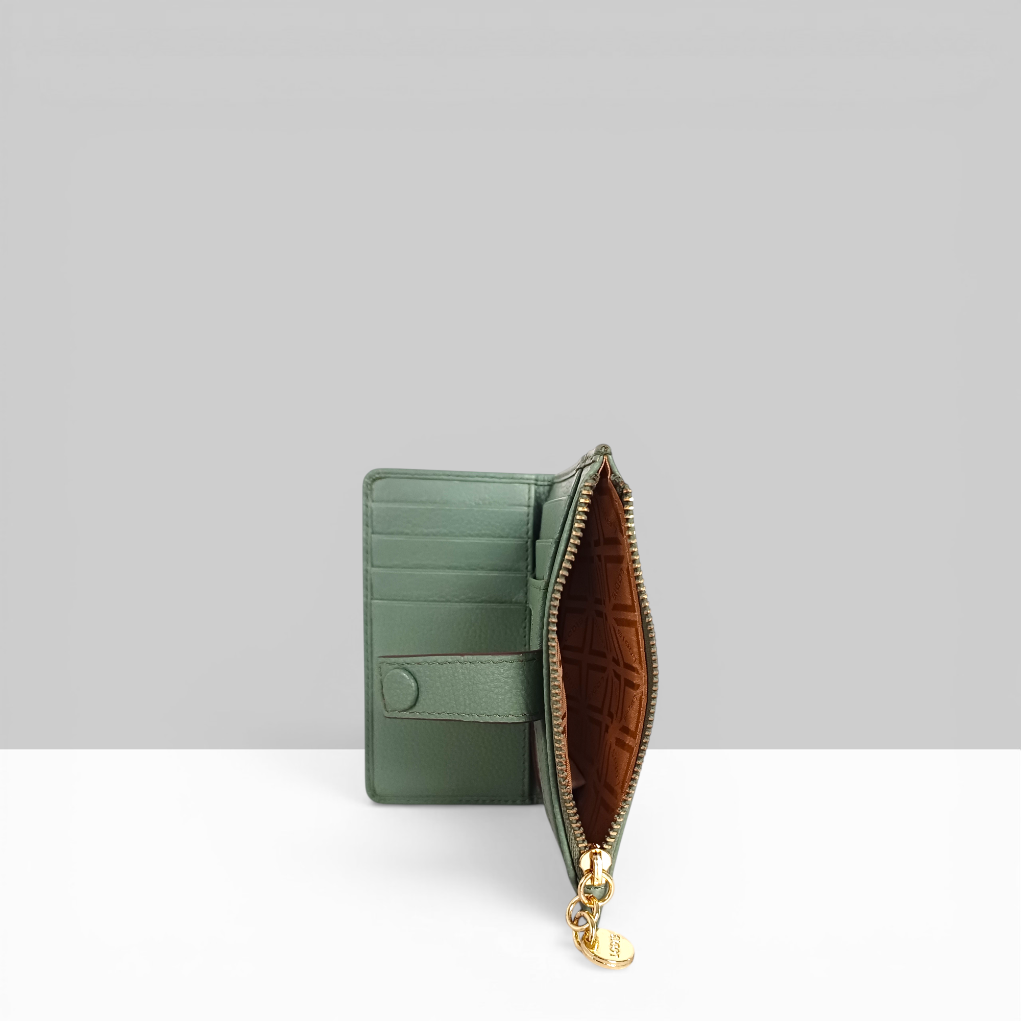 Lodis Kiara Flip Face Wallet in sage green pebbled leather open view showing card slots, tan interior lining, and gold zip closure