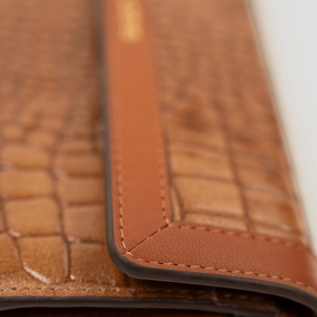 Lodis Amara Checkbook Clutch in Chestnut - Macro Detail of Smooth Texas Leather Flap Edge and Contrast Stitching Against Glossy Croco-Embossed Body | Lodis 1965