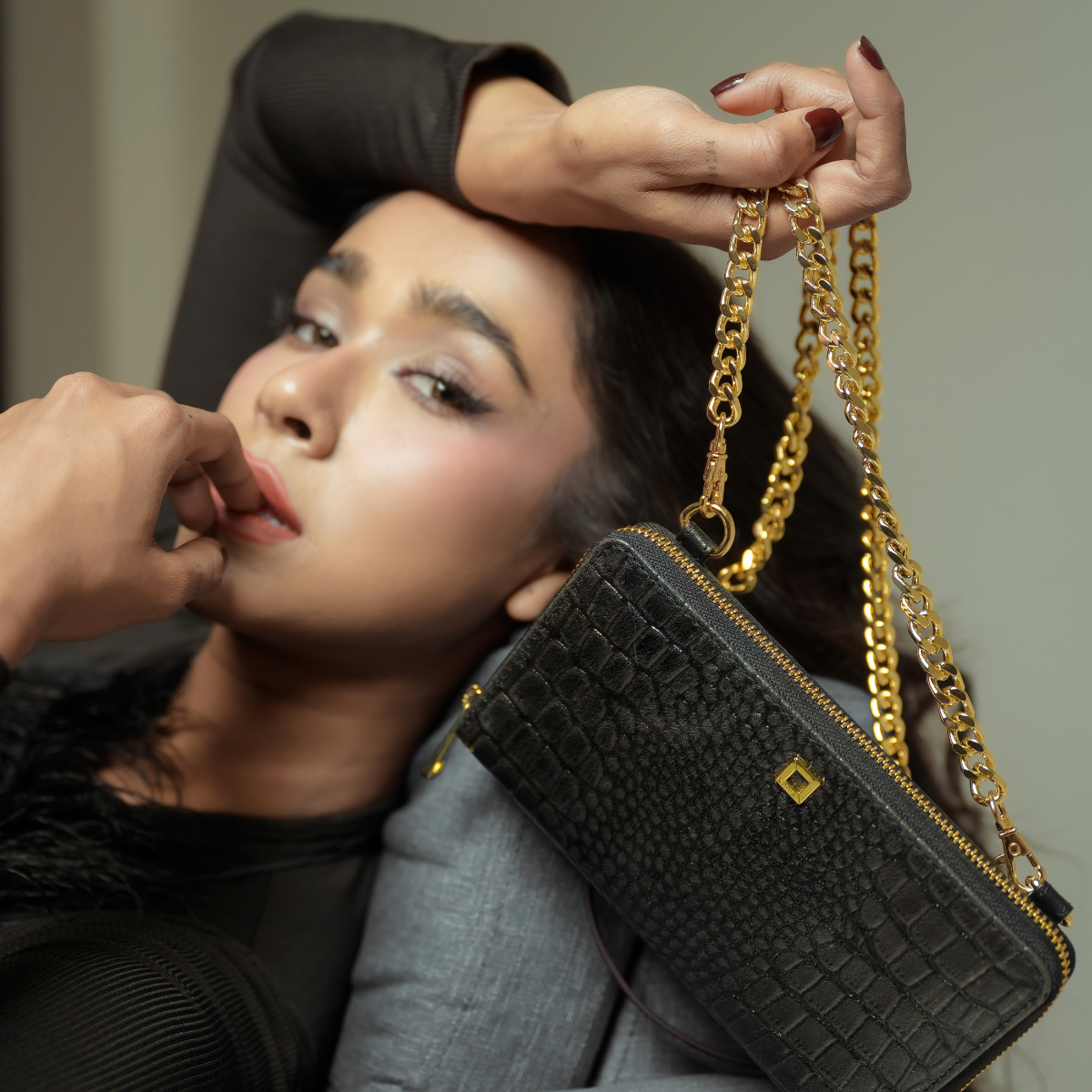 Woman Posing with Lodis Amara Sling in Black on Gold-Tone Chain Strap - Fall Lifestyle Shot with Black Top in Studio Setting, Glossy Croco-Embossed Leather | Lodis 1965