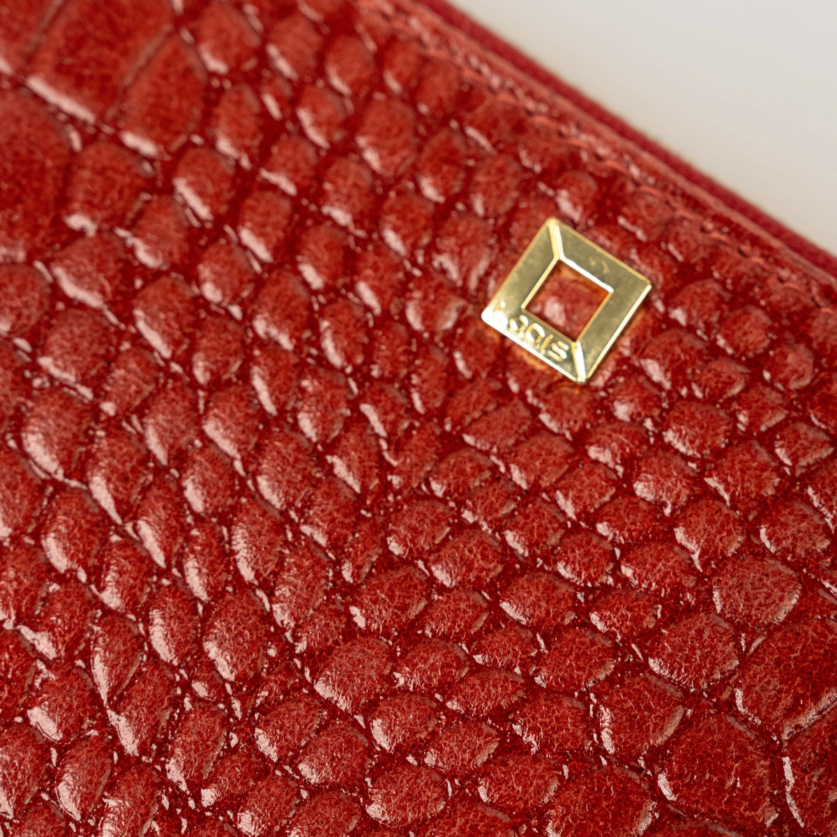 Lodis Amara Sling in Samba - Close-Up of Gold-Tone Square Logo Plate on Deep Red Glossy Croco-Embossed Leather | Lodis 1965