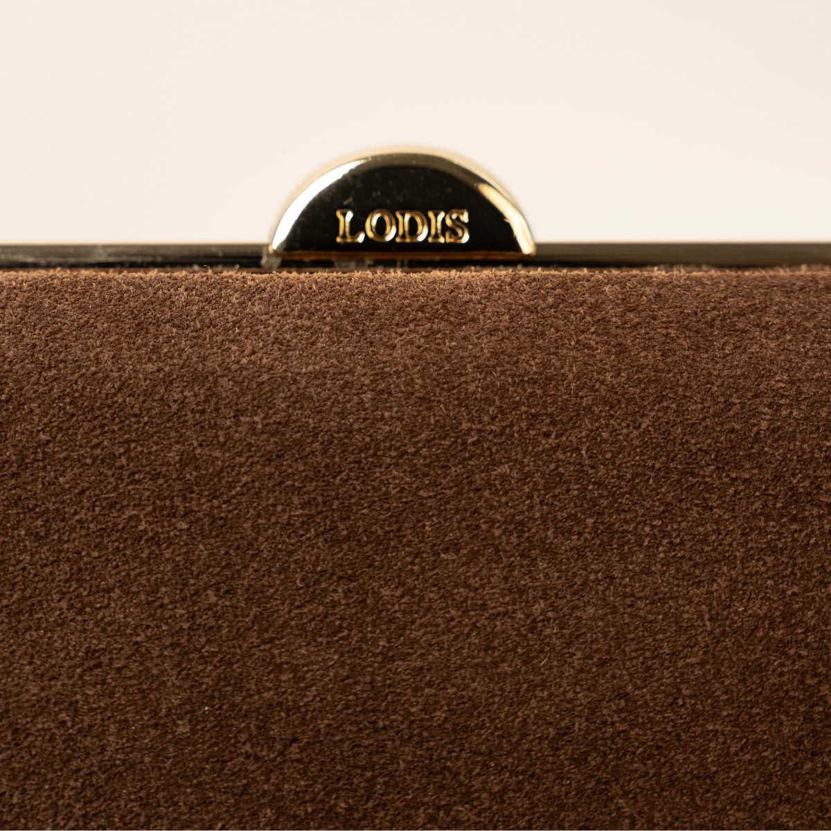 Lodis Celara Frame Clutch in Brown - Macro Detail of Lodis-Engraved Gold-Tone Clasp Above Plush Chocolate Brown Texas Suede | Lodis 1965