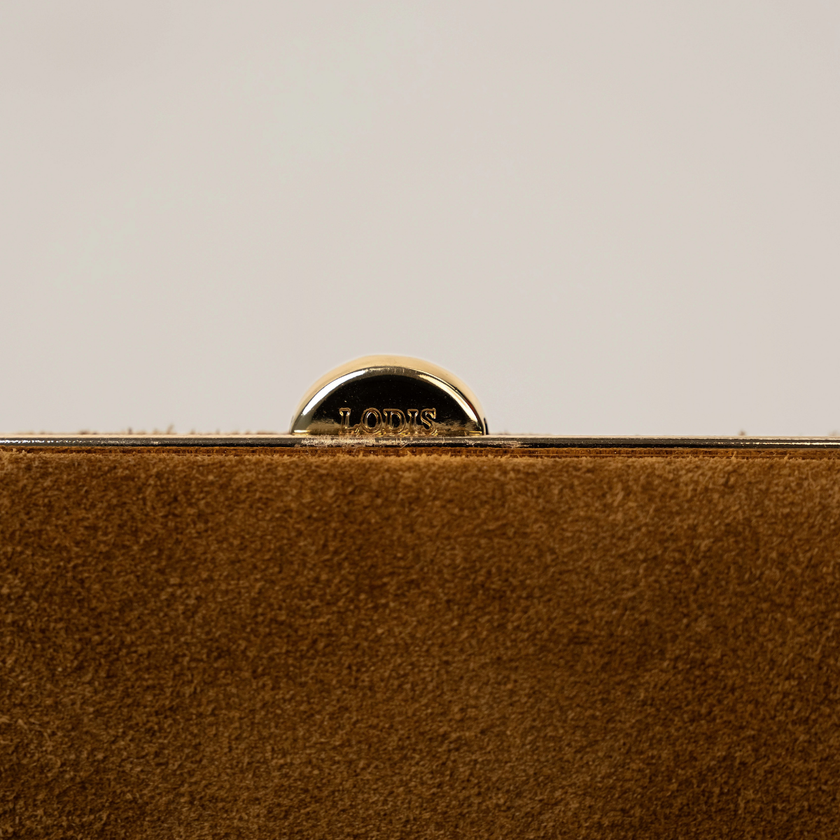 Lodis Celara Frame Clutch in Tan - Close-Up of Polished Gold-Tone Frame Clasp Engraved with Lodis Logo on Texas Suede | Lodis 1965