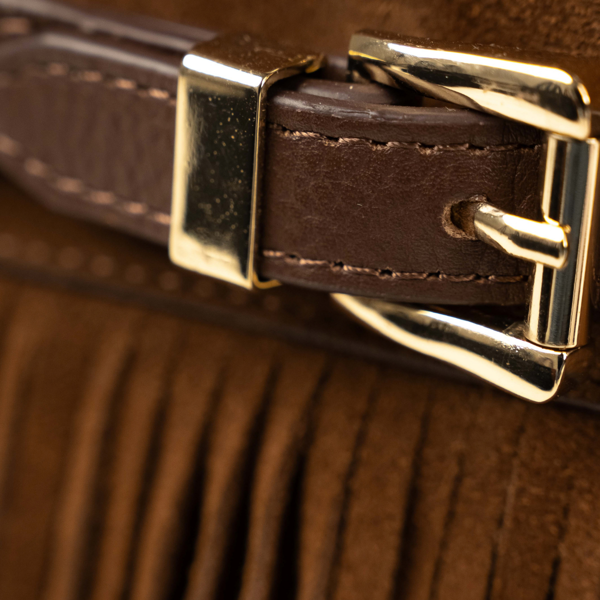 Lodis Ceres Satchel in Brown - Close-Up of Gold-Tone Buckle on Stitched Texas Leather Belt Above Suede Fringe | Lodis 1965