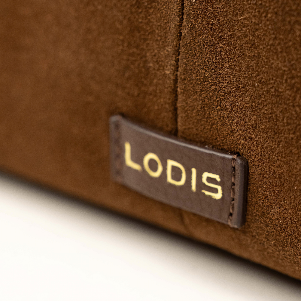 Lodis Ceres Satchel in Brown - Close-Up of Gold Foil Lodis Logo Leather Patch on Chocolate Brown Suede | Lodis 1965