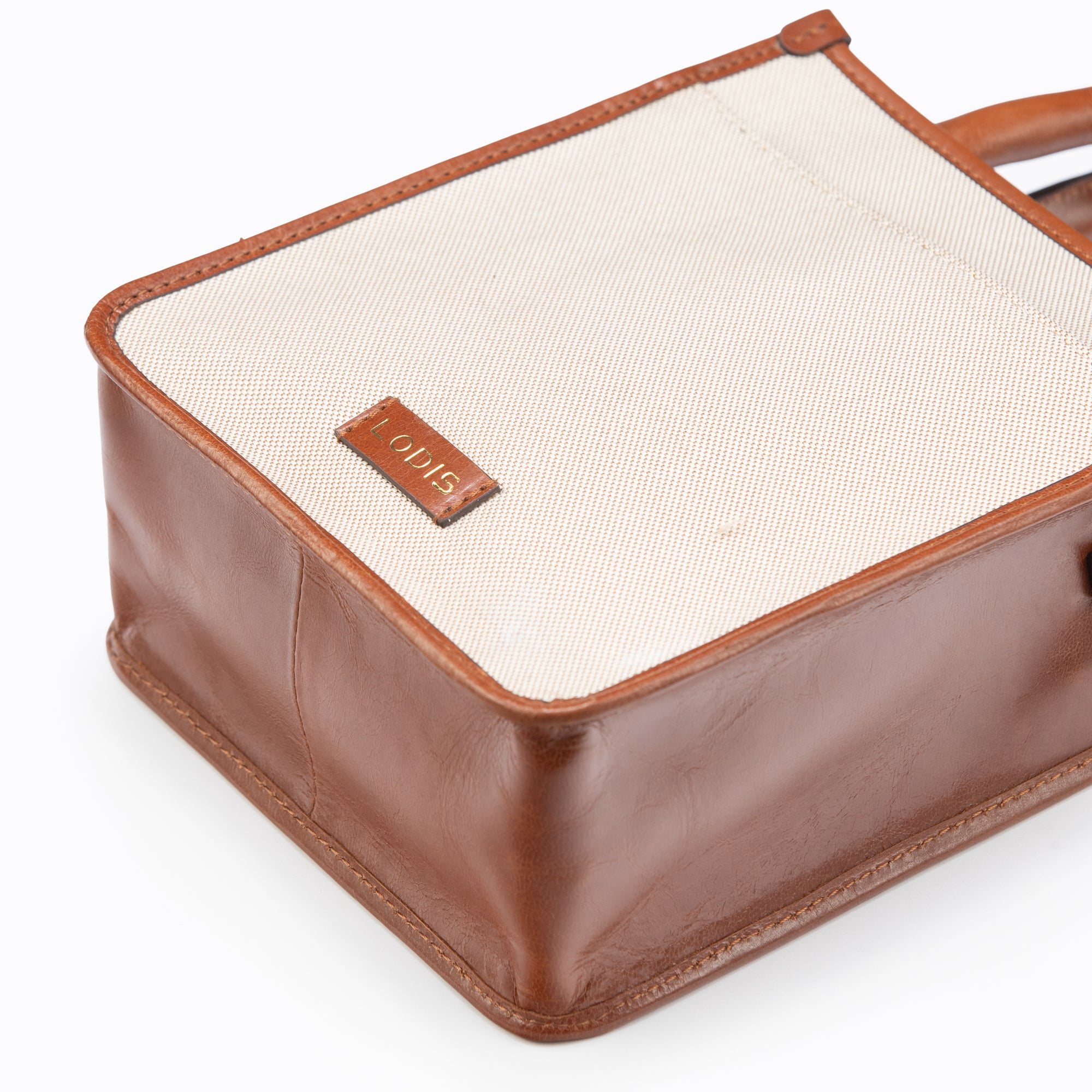 Lodis Kiara City Crossbody in Chestnut – Close-Up of Base and Logo Plate Showing Blended Fabric Texture and Chestnut Leather Detail | Lodis 1965