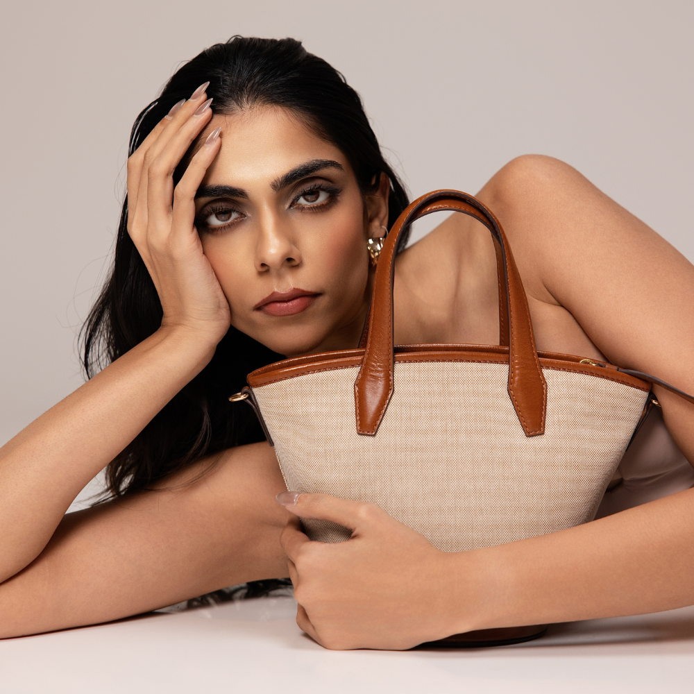 Woman Holding Lodis Kiara Small Bucket Bag in Chestnut – Close-Up Lifestyle Shot Showcasing Blended Fabric Body and Leather Handles | Lodis 1965
