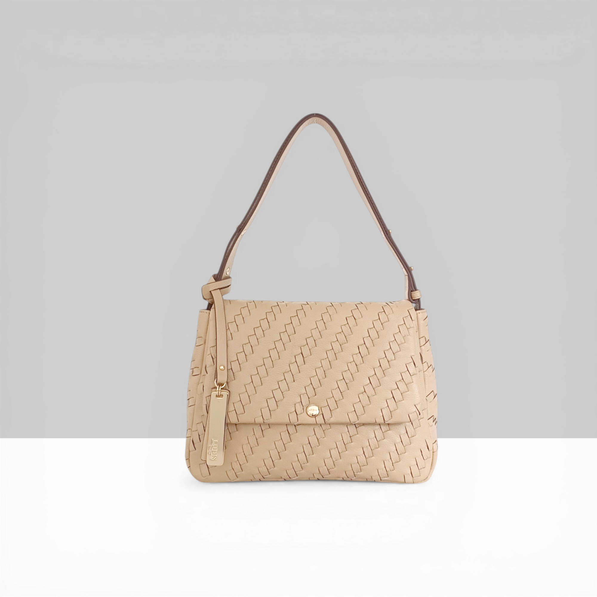 Lodis Solstice Shoulder Bag in Sand – Front View, Drum Dyed Woven Pebbled Leather with Flap Closure, Gold-Tone Snap and Tassel Detail | Lodis 1965