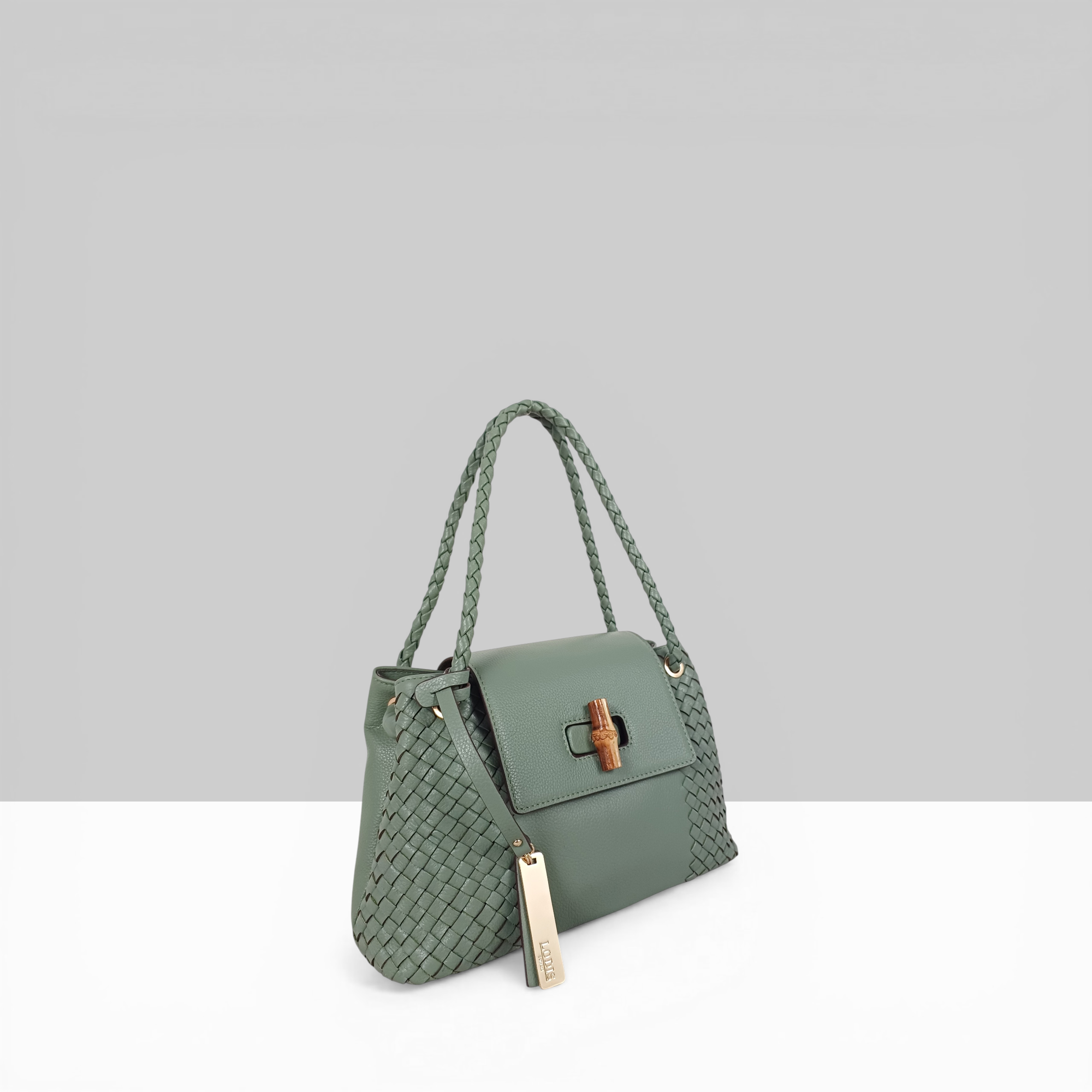Lodis Sondra Satchel in Sage Green – Angled View Showing Full Woven Leather Body, Braided Top Handle, Bamboo Turn-Lock Flap, and Gold-Tone Lodis Tag | Lodis 1965