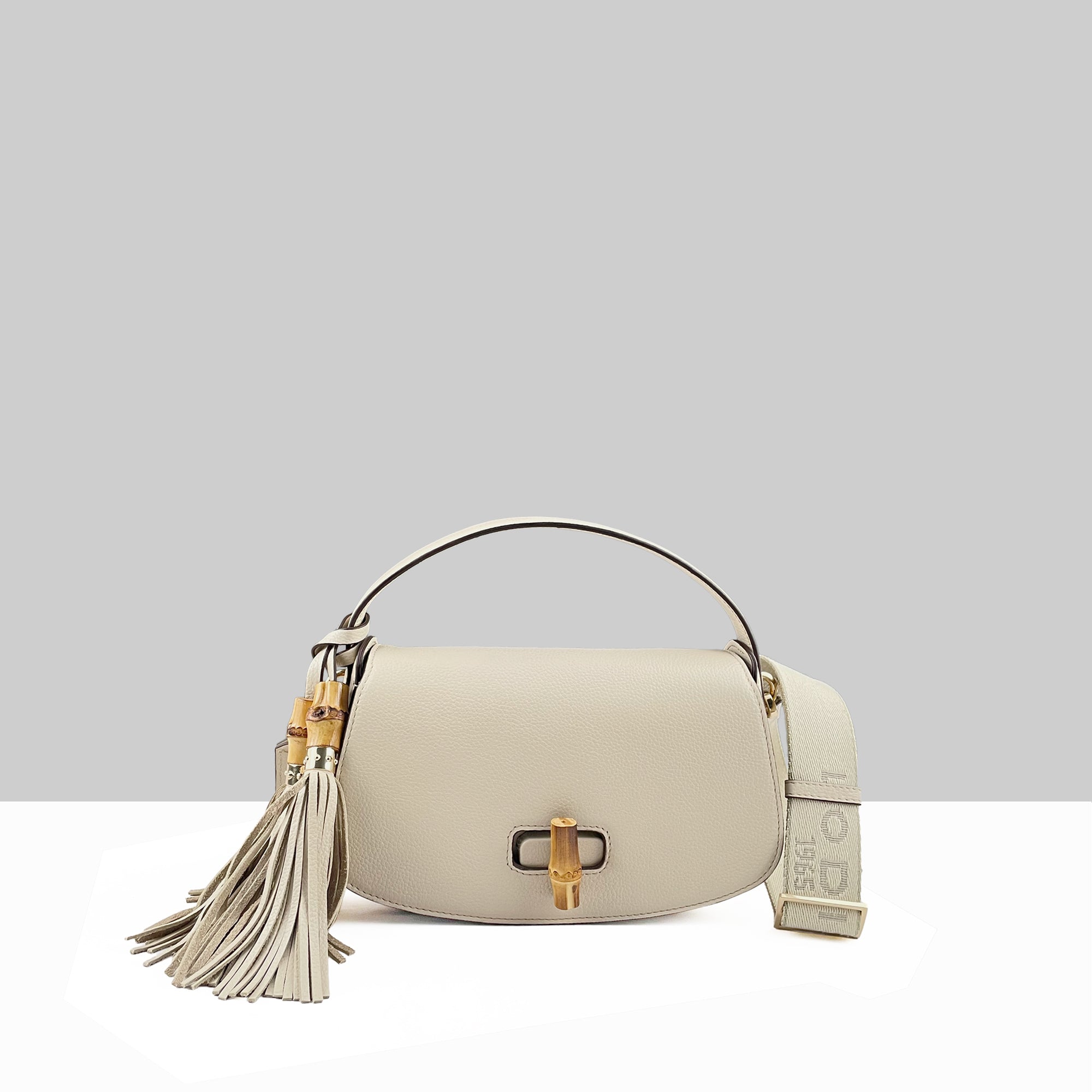 Lodis Sondra Top Handle Crossbody Bag in Sand – Front View, Drum Dyed Pebbled Leather with Gold-Tone Bamboo Turn-Lock, Double Tassel, and Branded 1965 Woven Strap | Lodis 1965