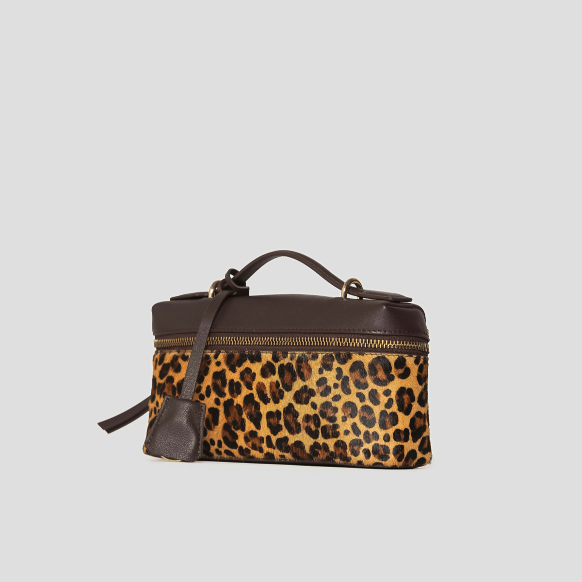 Lodis Stratos Texas Crossbody in Cheetah Print - Three-Quarter View Showing Hair Calf Front Panel, Leather Hang Tag and Structured Box Shape | Lodis 1965