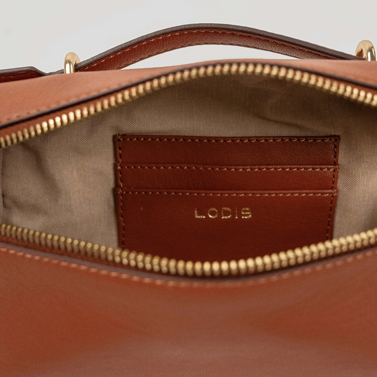 Lodis Stratos Texas Crossbody in Rust - Interior View Showing Zip-Around Opening, Leather Slip Pocket with Lodis Logo and Light Fabric Lining | Lodis 1965